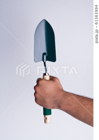 Hand's holding garden trowel. 61363994