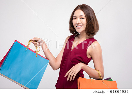Shopping Asian woman with short hairs smile wearing red dress Holding Shopping bags,Cheerful and Happiness enjoy shopping in black friday sale,Isolated on gray background 61364982