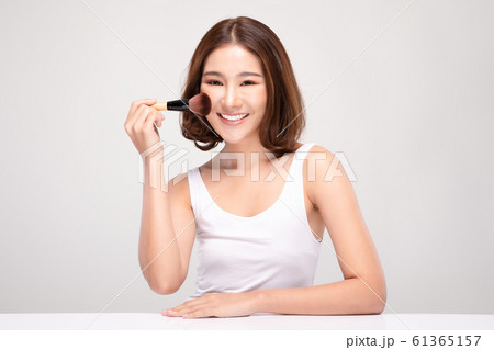 Beautiful Asian young woman smile and holding make up brush with healthy Clean and Fresh skin feeling so happiness and cheerful,Isolated on white background,Beauty Cosmetics Concept 61365157