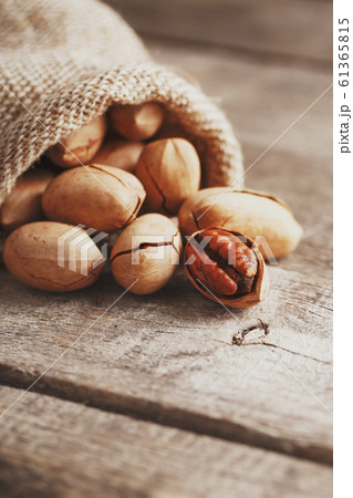 Pecans are spilled out of a burlap bag onto a Pecans are spilled out of a burlap bag onto a 61365815