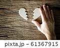 woman hand holding broken heart paper cut on wooden background 61367915