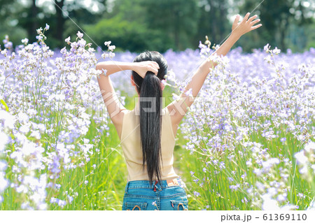 back view portrait of beautiful woman having a happy time and enjoying among flower 61369110