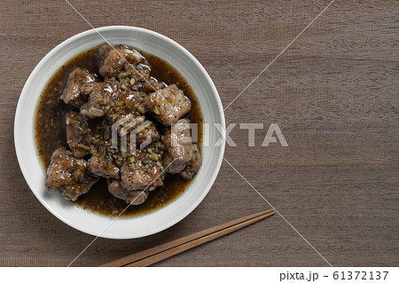 top view of stir fried pork rib with black pepper sauce in a ceramic dish on wooden table.  61372137