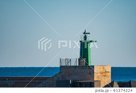 Green painted lighthouse over concrete and clear sky 61374324