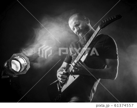Bearded man playing guitar with spotlight Bearded man playing guitar with spotlight 61374557