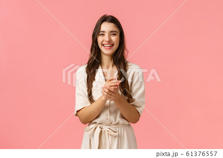 Happy and cheerful girl talking to friend as applying hand cream, body lotion, smiling and laughing carefree, standing pink background in soft tender dress, using cosmetics, hygiene products Happy and cheerful girl talking to friend as applying hand cream, body lotion, smiling and laughing carefree, standing pink background in soft tender dress, using cosmetics, hygiene products 61376557