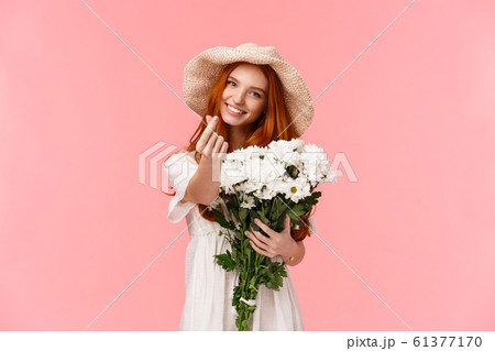 Love, relationship and celebration concept. Cute and silly charismatic redhead girlfriend express care and tenderness, receive beautiful bouquet flowers, holding it and making heart korean gesture 61377170