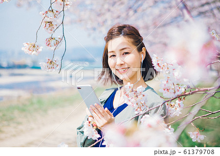 桜の木の下で音楽を聴く女性 61379708
