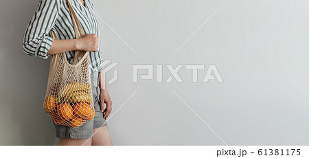 woman standing with mesh bag on shoulder woman standing with mesh bag on shoulder 61381175