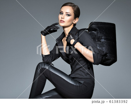 Beautiful woman in black holds fashion handbag Beautiful woman in black holds fashion handbag 61383392