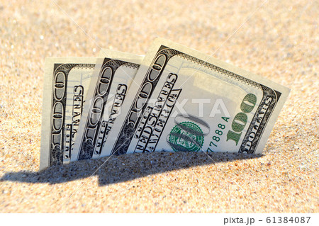 Money dolars half covered with sand lie on beach close-up. Money dolars half covered with sand lie on beach close-up. 61384087