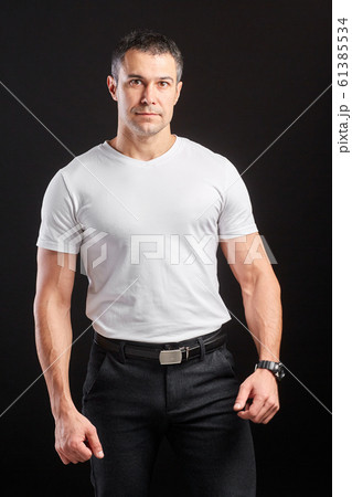 Handsome Athletic man in white blank t-shirt standing on black wall background Handsome Athletic man in white blank t-shirt standing on black wall background 61385534
