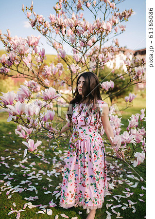 Charming girl stand by the beautiful pink magnolia tree outside. Gorgeous lady Charming girl stand by the beautiful pink magnolia tree outside. Gorgeous lady 61386086