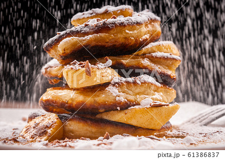 Pancakes with chocolate and banana and powdered sugar falling on top Pancakes with chocolate and banana and powdered sugar falling on top 61386837