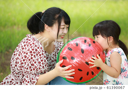 スイカのビーチボールを膨らます親子の写真素材