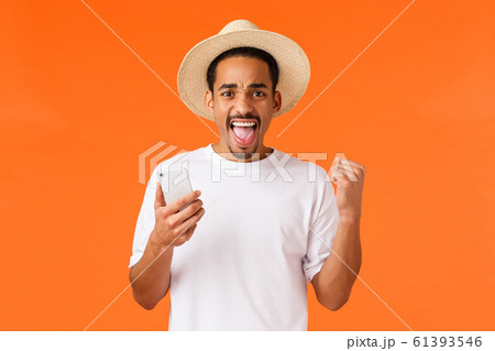 Happy satisfied african-american man on vacation, received great news message, triumphing, fist pump saying yes, holding smartphone, celebrating, booked plain tickets ready for travel 61393546