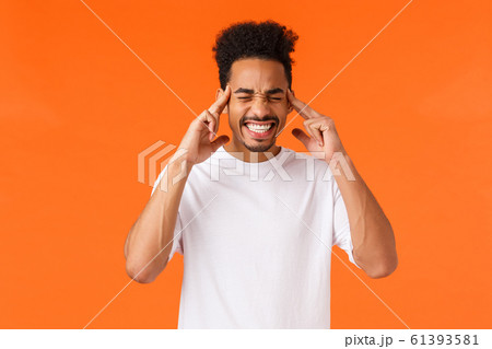 Distressed and tensed african-american male in white t-shirt, clench teeth, close eyes and touch temples, feeling migraine or headache, trying calm down and think straight, orange background 61393581