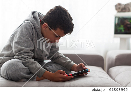 Child with portable games console. video game console for home or portable gaming. Teenager man playing game on console Child with portable games console. video game console for home or portable gaming. Teenager man playing game on console 61393946