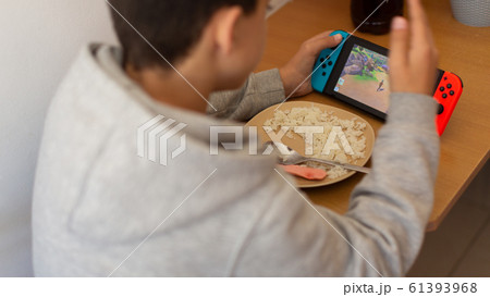 Kid eating rice and surfing on internet or playing video games on console. boy eats poorly distracted by the game. Kid eating rice and surfing on internet or playing video games on console. boy eats poorly distracted by the game. 61393968