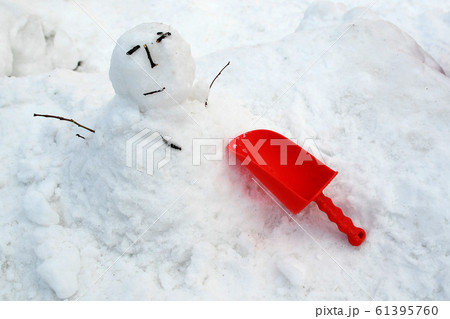 雪で子どもたちが遊んだ後に残ったスコップと雪だるまの写真素材