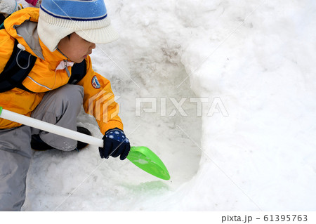 夢中で雪山を掘っている男の子の真剣な遊び 61395763
