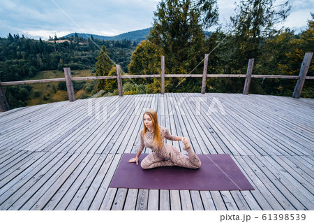A woman practices yoga at the morning in a terrace on a fresh air. A woman practices yoga at the morning in a terrace on a fresh air. 61398539