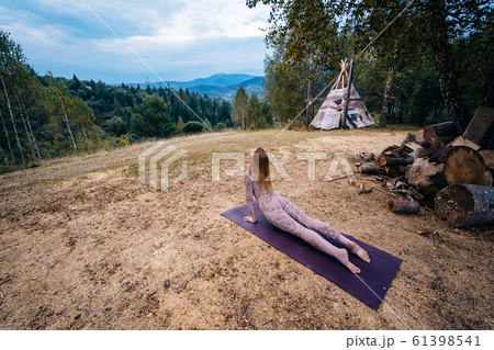 A woman practices yoga at the morning in a park on a fresh air. 61398541
