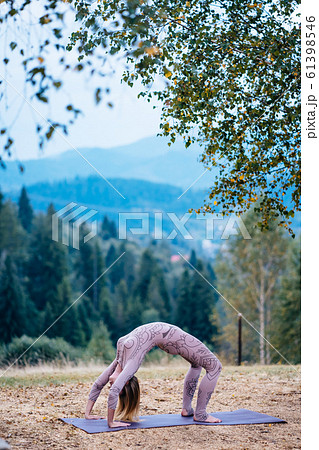 A woman practices yoga at the morning in a park on a fresh air. 61398546