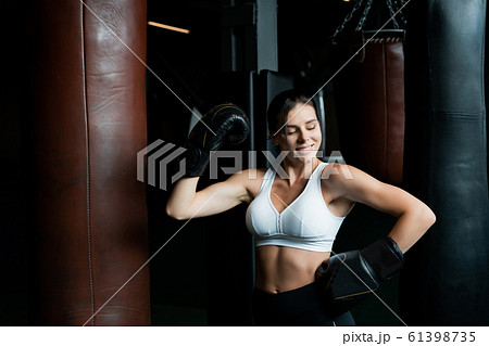 Boxing woman posing with punching bag, on dark background. Strong and independent woman concept 61398735