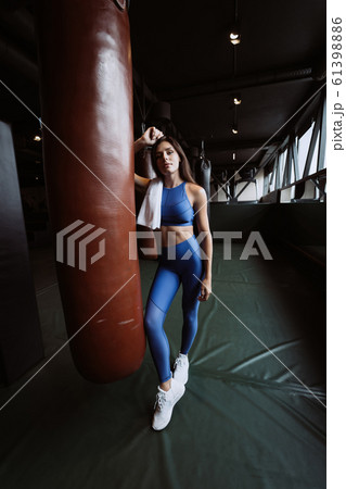 Smiling fit girl holding towel and taking rest in gym near punching bag 61398886