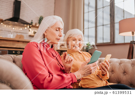Two pleasant-looking elderly grey-haired women looking involved 61399531