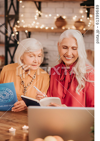 Two grey-haired pleasant cute ladies looking interested while studying together 61399689
