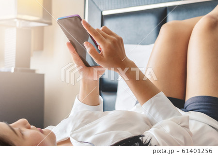 Happy woman lay on bed while surfing internet and send message on smartphone 61401256
