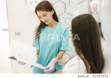 Female cosmetologist speak with woman and show result of previous work. Cosmetology clinic Female cosmetologist speak with woman and show result of previous work. Cosmetology clinic 61403650
