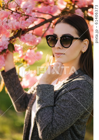 Portrait of beautiful woman in sunglasses stand by the pink tree 61406373