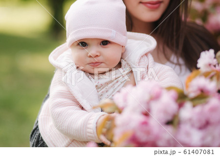 Mother show firs time to her daughter pink tree. Happy baby hold branch of sakura 61407081