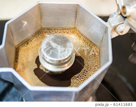 Italian traditional coffeemaker with hot coffee flowing out from the spout Italian traditional coffeemaker with hot coffee flowing out from the spout 61411683