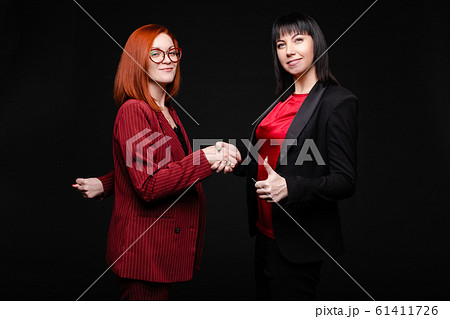 Smiling pretty businesswomen shaking hands to each Smiling pretty businesswomen shaking hands to each 61411726