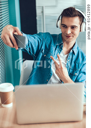 Smiling young man using mobile phone at workplace 61412899