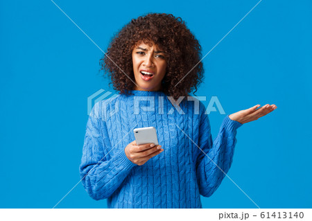 Wtf going on, someone explain me. Confused and frustrated bothered african-american woman in winter sweater, shrugging raise hand in dismay look questioned and pissed, holding smartphone Wtf going on, someone explain me. Confused and frustrated bothered african-american woman in winter sweater, shrugging raise hand in dismay look questioned and pissed, holding smartphone 61413140