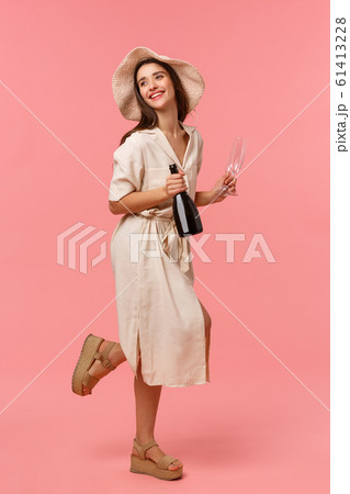 Full-length vertical shot woman on picnic, going out with girlfriend on fine sunny day in hat and dress, rushing with bottle champagne and glasses, smiling happily, standing pink background Full-length vertical shot woman on picnic, going out with girlfriend on fine sunny day in hat and dress, rushing with bottle champagne and glasses, smiling happily, standing pink background 61413228