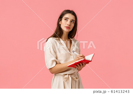 Inspiration, creativity and education concept. Concentrated pensive and creative young girl using imagination, thinking looking up wondered stop for second as writing something in red notebook Inspiration, creativity and education concept. Concentrated pensive and creative young girl using imagination, thinking looking up wondered stop for second as writing something in red notebook 61413243