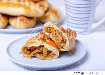 Pies (pirozhki) with cabbage. Homemade baking. Traditional Russian and Ukrainian cuisine. In the background is a dish with pies. Close-up. Pies (pirozhki) with cabbage. Homemade baking. Traditional Russian and Ukrainian cuisine. In the background is a dish with pies. Close-up. 61413656