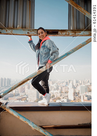 Smiling pretty Asian lady enjoying day on roof Smiling pretty Asian lady enjoying day on roof 61414391