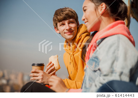 Happy young guy holding sandwich on the roof 61414443