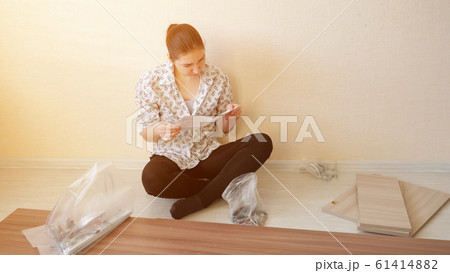housewife sits and reads instruction looking at fasteners housewife sits and reads instruction looking at fasteners 61414882