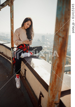 Smiling pretty girl looking on phone screen on roof 61415345