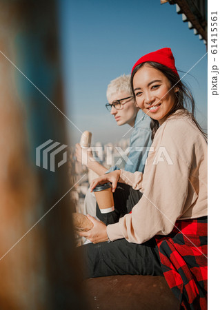 Happy Asian lady holding coffee on the roof Happy Asian lady holding coffee on the roof 61415561