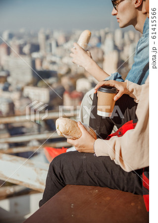 Young woman sitting with hot dring on the rooftop Young woman sitting with hot dring on the rooftop 61415566