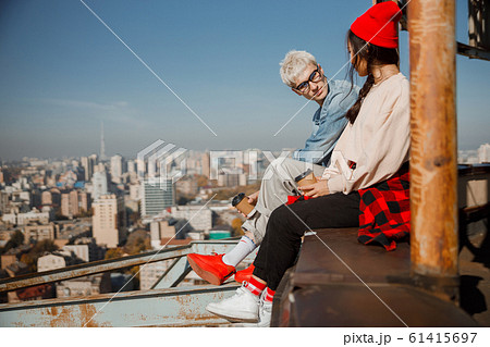 Young guy in glasses looking at girlfriend on roof 61415697